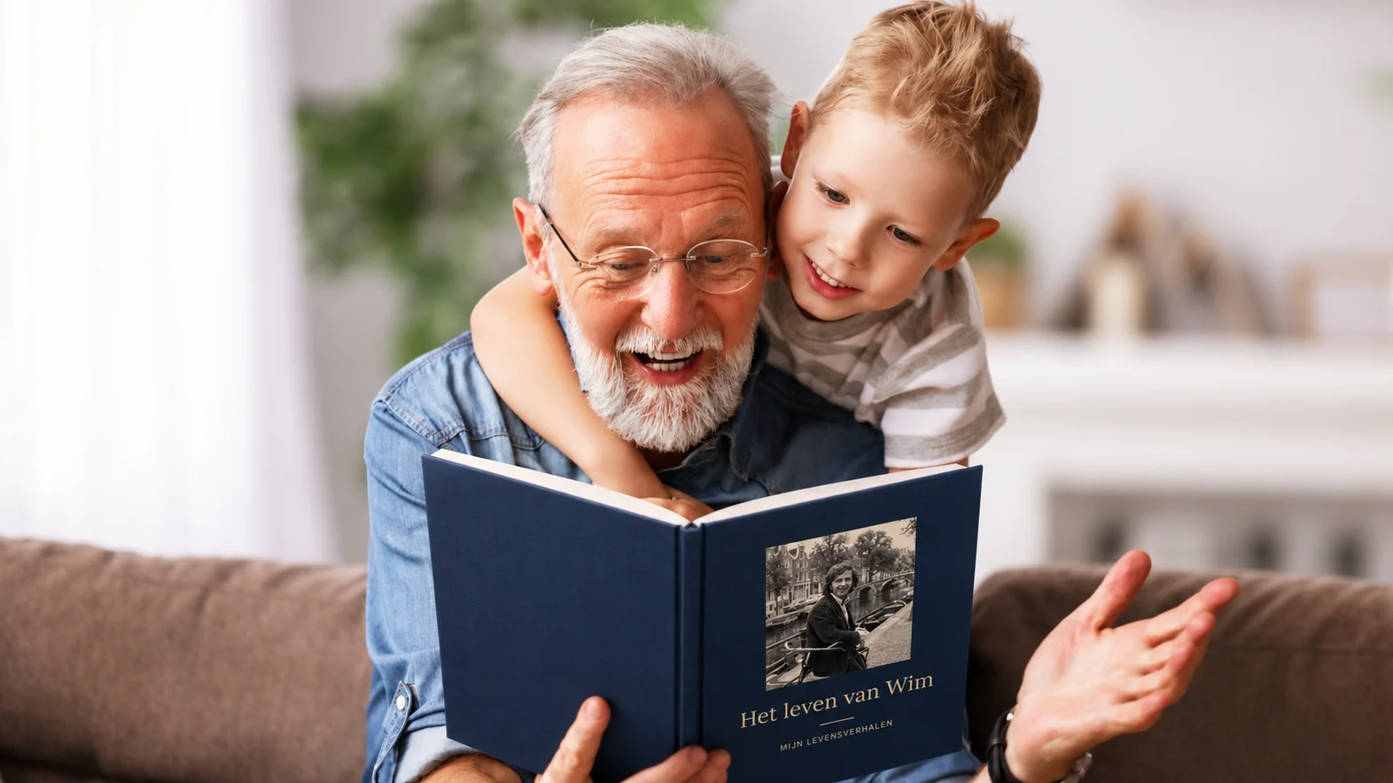 Un grand-père lit avec son petit-fils, sur le canapé, le livre Nos Histoires